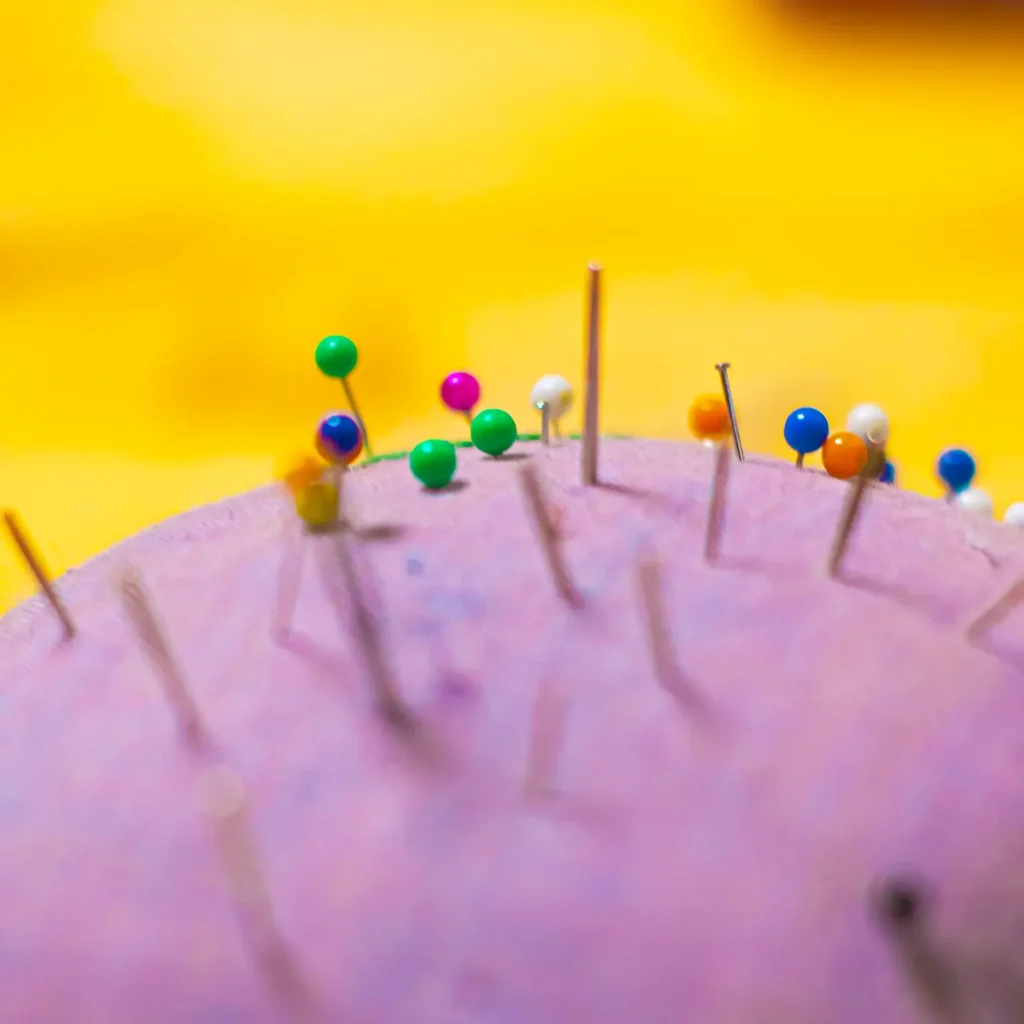 (Närbild på nålar med färglada nålhuvuden, i en nålkudde. Foto: Andreas Melin)