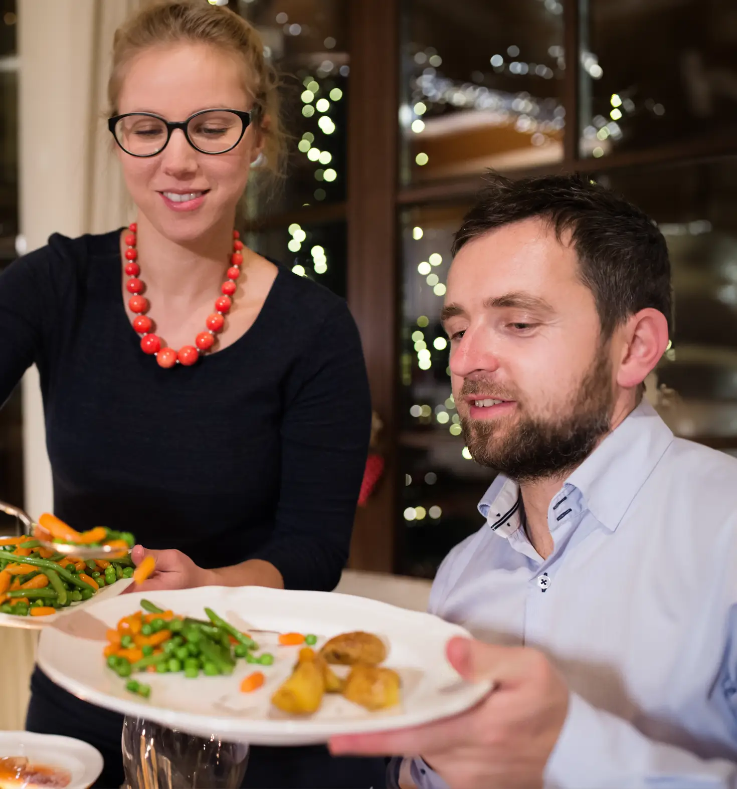 kvinna serverar man mat på en tallrik.
