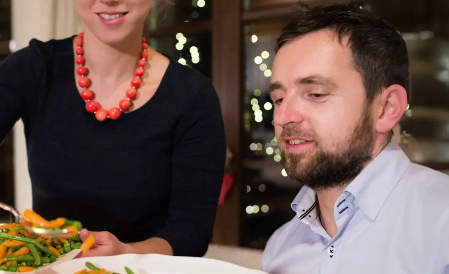 kvinna serverar man mat på en tallrik.